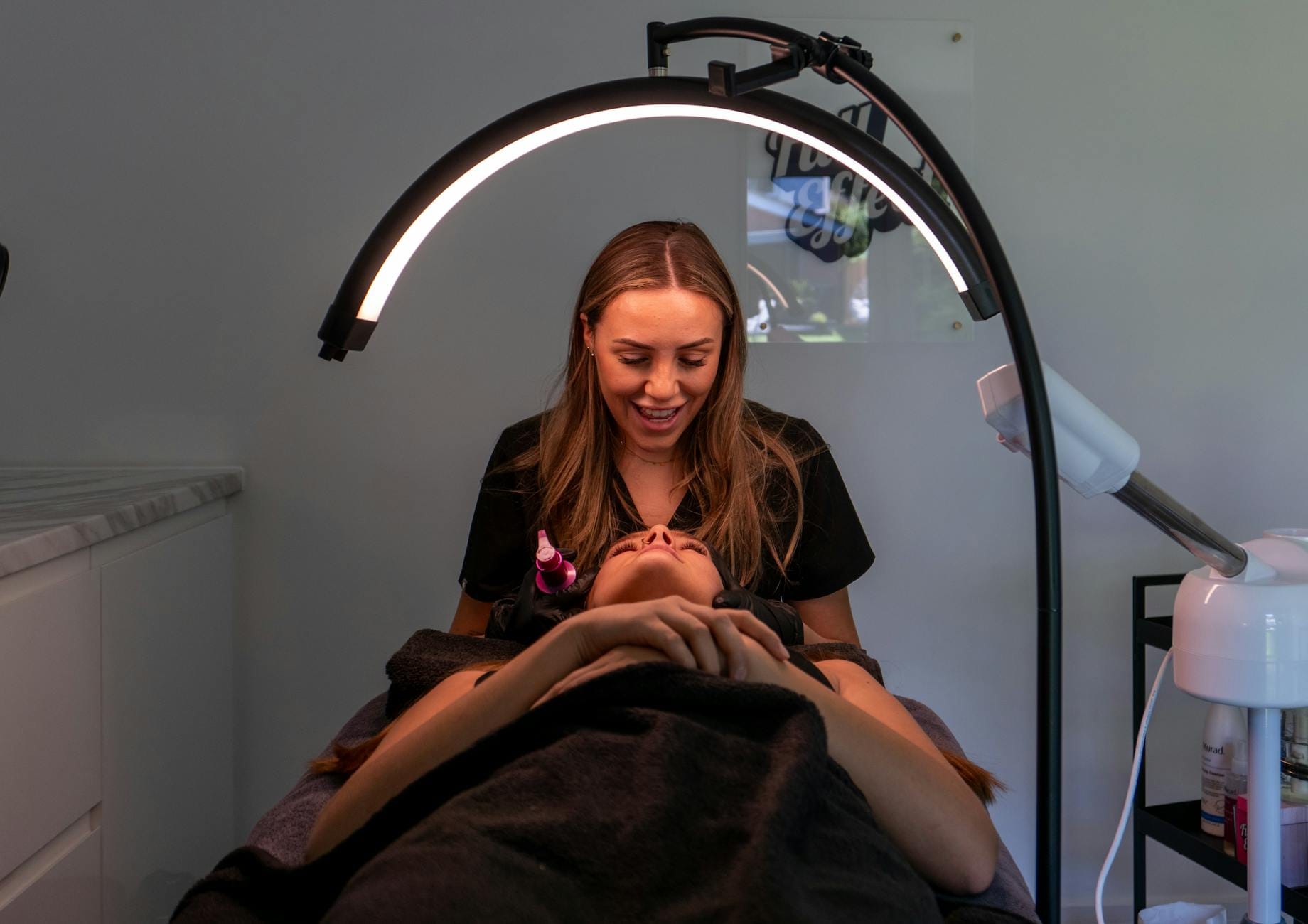 Kosmetyczka wykonuje zabieg na twarzy klientki w nowoczesnym spa