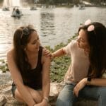 Dwie kobiety szczerze rozmawiają nad słonecznym jeziorem