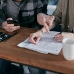 Cennik „od do”: jak pytać o wycenę, żeby dostać konkrety bez niespodzianek Para przy stole analizuje dokumenty finansowe i liczy koszty opieki