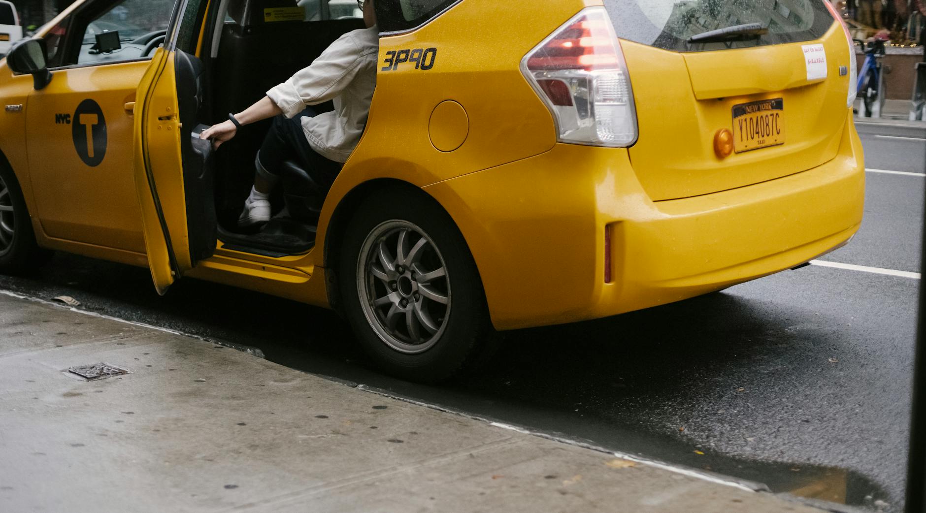 Kiedy lepiej wybrać taxi dla zwierząt zamiast własnego auta? Pasażer zamyka drzwi żółtej taksówki stojącej przy miejskim chodniku
