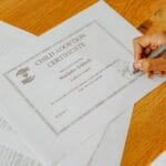 Dłoń podpisująca oficjalny dokument na biurku