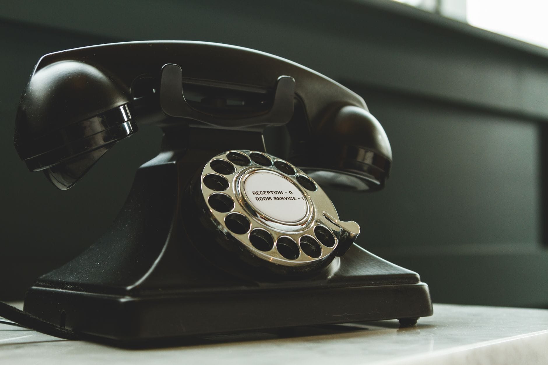 Czarny telefon z tarczą na ladzie recepcji hotelu