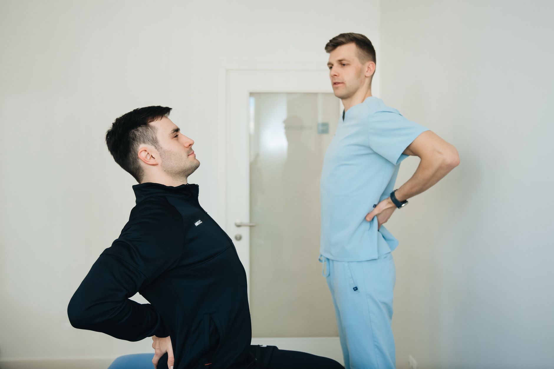 Fizjoterapeuta pokazuje pacjentowi ćwiczenia na kręgosłup w gabinecie