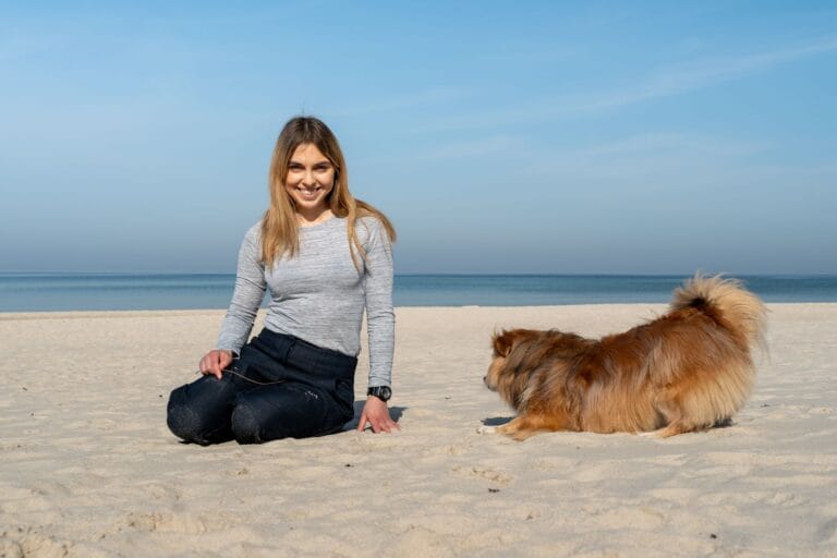 Kobieta bawi się z psem na słonecznej plaży w Kołobrzegu